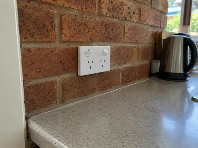 Double power point on a brick kitchen splashback above a benchtop in Labrador