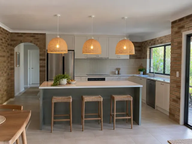 Three woven pendant lights over a kitchen island in a brick-walled home in Biggera Waters